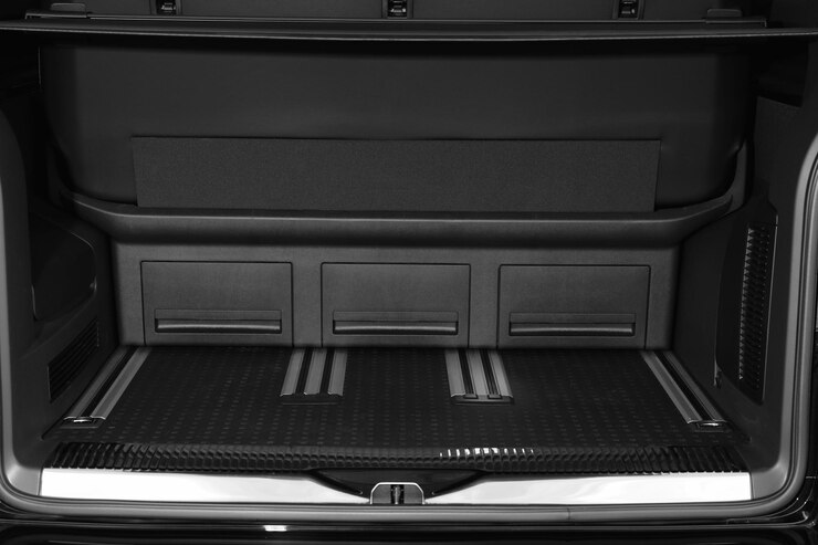 Close-up view of a clean and organized car trunk with built-in storage compartments and rubberized floor lining.