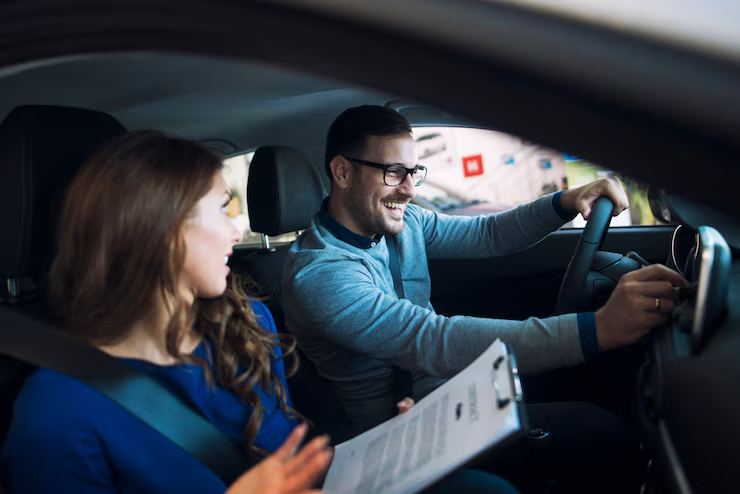 Happy couple evaluating a vehicle during a test drive, discussing how many miles is good for a used car.