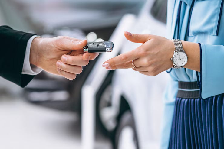 "Close-up of a person handing over a car key to another individual, symbolizing car sale, rental, or lease agreement."